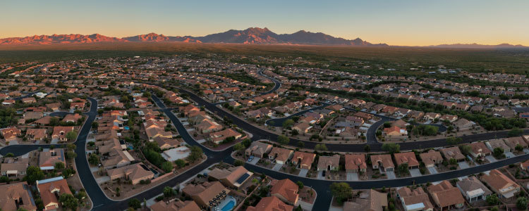 Aerial view of a homeowners association community filled with HOA homes with a mountain and the skyline in the background.