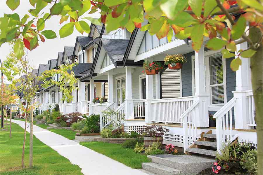 A row of white and grey nicely kept houses in an HOA management community that all look the same.