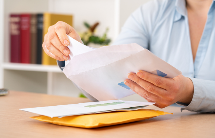 HOA volunteer sitting at a desk putting an hoa statement into an envelope to mail to hoa community members